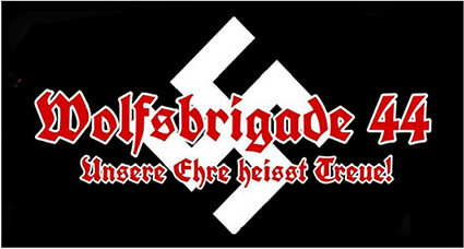 Weiß umrandeter roter Schriftzug in gebrochener Schrift „Wolfsbrigade 44 Unsere Ehre heißt Treue“ vor einem weißen Hakenkreuz auf schwarzem Grund