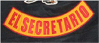 Das Kennzeichen zeigt einen nach untenhin gerundeten, gelben Bogen mit roter Umrandung. Es enthält die Funktionsbeschreibung „EL SECRETARIO“, übersetzt Sekretär, in roten Großbuchstaben.