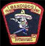 Dieses schwarze Kennzeichen mit roter Umrandung in Form eines umgekehrten Trapezes, zeigt einen nach links blickenden dickbäuchigen Mann mit Sombrero, in dem sich zwei Einschusslöcher befinden. Pistole und Schwert hält er in den Händen. Oberhalb des Mannes befindet sich ein gelbes Banner mit roter Umrandung, das in roten Großbuchstaben die Wortfolge „1 Prozent BANDIDOS MC“ enthält. Unterhalb des Mannes ist ein gelbes Banner mit roter Umrandung zu sehen, das in roten Großbuchstaben die Jahresangabe „FIFTEEN YEARS“, übersetzt fünfzehn Jahre, anzeigt.