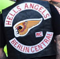 Sogenannter „Fullcolour“ des „HAMC Berlin Central“ bestehend aus den kreisförmig angeordneten Schriftzügen „HELLS ANGELS“ (oben, sogenannter „Toprocker“) und „BERLIN CENTRAL“ (unten, sogenannter „Bottomrocker“) mit roter Schrift auf weißem Grund, weiß umrandet, Schriftart „hessian regular“, und dem geflügelten Totenkopf in den Farben schwarz, weiß, gelb, rot, weiß umrandet (mittig, sogenannter „Death Head“ als sogenannter „Centerpatch“) zuzüglich der Buchstaben „MC“ für „Motorcycle Club“ in roter Schrift auf weißem Grund, weiß umrandet (rechtsseitig unterhalb des „Death Head“ angeordnet)