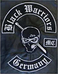 Kombination aus den vier Komponenten Toprocker (oben) mit dem Schriftzug „Black Warriors“, Center-Patch (Mitte) mit einem stilisierten Schädel samt Augenmaske (Samurai-Kämpfer) und Samurai-Schwert, seitlichem Schriftzug (rechts) „MC“ sowie Bottomrocker (unten) mit dem Schriftzug „Germany“.