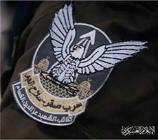 Das Logo des Saqr-Geschwaders der AL-QASSAM-Brigaden zeigt einen Greifvogel, der einen Pfeil hält. Im Hintergrund sind die Kuppeln des Felsendoms und der Al-Aqsa-Moschee in Jerusalem zu sehen. Zu lesen ist: Saqr-Geschwader – Luftwaffe (Saqr: arabisch für Falke). Darunter der Name der Brigaden des Märtyrers Izz-al-Din-al-Qassam (unten rechts: „militärische Medien“).