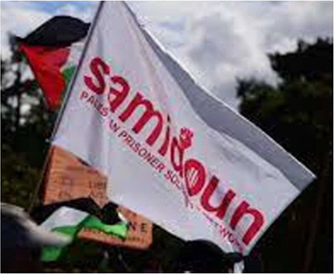 Als Symbol verwendet Samidoun den Vereinsnamen „Samidoun – PALESTINIAN PRISONER SOLIDARITY NETWORK“; häufig in roter Schrift auf weißem oder in weißer Schrift auf rotem oder orangefarbenen Untergrund. Das Wort „Samidoun“ wird hierbei durchweg in Minuskeln geschrieben. Der im Wort enthaltene Buchstabe „d“ wird am oberen Ende des Abstrichs mit dem gezeichneten Abbild einer geballten rechten Faust abgeschlossen, bei der die Handfläche zum Betrachter zeigt. Der Bauch des „o“ ist mit drei dünnen vertikalen Linien in gleichmäßigem Abstand zueinander versehen. Unter dem größeren Wort „Samidoun“ findet sich kleiner die Bezeichnung „Palestinian Prisoner Solidarity Network“. Die Bezeichnung ist durchweg in Majuskeln abgebildet und nicht mit weiteren optischen Merkmalen versehen. Dieser Teil des Schriftzugs hat insgesamt annähernd dieselbe Breite wie der darüber liegende „Samidoun“-Teil und ca. ein Drittel von dessen Höhe. Je nach Hintergrundfarbe wird der Schriftzug-Bestandteil „Samidoun“ in unterschiedlichen Farben dargestellt. Bei einem weißen Hintergrund ist der Schriftzug-Bestandteil in roter Farbe abgebildet. Bei rotem Hintergrund ist er in weißer Farbe abgebildet. Der Schriftzug-Bestandteil „Palestinian Prisoner Solidarity Network“ kann, abhängig vom Hintergrund, in schwarzer, weißer oder roter Farbe abgebildet sein.