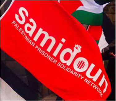 Als Symbol verwendet Samidoun den Vereinsnamen „Samidoun – PALESTINIAN PRISONER SOLIDARITY NETWORK“; häufig in roter Schrift auf weißem oder in weißer Schrift auf rotem oder orangefarbenen Untergrund. Das Wort „Samidoun“ wird hierbei durchweg in Minuskeln geschrieben. Der im Wort enthaltene Buchstabe „d“ wird am oberen Ende des Abstrichs mit dem gezeichneten Abbild einer geballten rechten Faust abgeschlossen, bei der die Handfläche zum Betrachter zeigt. Der Bauch des „o“ ist mit drei dünnen vertikalen Linien in gleichmäßigem Abstand zueinander versehen. Unter dem größeren Wort „Samidoun“ findet sich kleiner die Bezeichnung „Palestinian Prisoner Solidarity Network“. Die Bezeichnung ist durchweg in Majuskeln abgebildet und nicht mit weiteren optischen Merkmalen versehen. Dieser Teil des Schriftzugs hat insgesamt annähernd dieselbe Breite wie der darüber liegende „Samidoun“-Teil und ca. ein Drittel von dessen Höhe. Je nach Hintergrundfarbe wird der Schriftzug-Bestandteil „Samidoun“ in unterschiedlichen Farben dargestellt. Bei einem weißen Hintergrund ist der Schriftzug-Bestandteil in roter Farbe abgebildet. Bei rotem Hintergrund ist er in weißer Farbe abgebildet. Der Schriftzug-Bestandteil „Palestinian Prisoner Solidarity Network“ kann, abhängig vom Hintergrund, in schwarzer, weißer oder roter Farbe abgebildet sein.