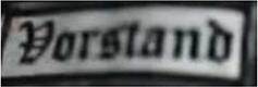 Dieses weiße Kennzeichen mit schwarzer Umrandung in Form eines Rechtecks enthält die Funktionsbeschreibung „Vorstand“ in schwarzen Buchstaben. Es deutet auf die Vorstandsmitglieder der Gruppierung hin.