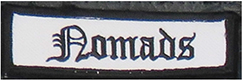 Dieses weiße Kennzeichen mit schwarzer Umrandung in Form eines Rechtecks enthält die Funktionsbeschreibung „Nomads“, übersetzt Nomade, in schwarzen Buchstaben.