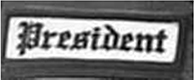 Dieses weiße Kennzeichen mit schwarzer Umrandung in Form eines Rechtecks enthält die Funktionsbeschreibung „President“, übersetzt Präsident, in schwarzen Buchstaben.