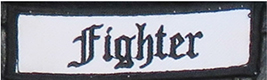 Dieses weiße Kennzeichen mit schwarzer Umrandung in Form eines Rechtecks enthält die Aufschrift „Fighter“, übersetzt Kämpfer, in schwarzen Buchstaben.