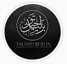 Auf schwarzem Hintergrund mit weißer Umrandung in weißer Schrift abgebildete kalligraphische Darstellung der arabischen Worte „Tauhid Berlin“. Darunter befindet sich in weißer lateinischer Schrift der Schriftzug „Tauhid Berlin“ mit weißem darunter befindlichen Schriftzug „Kernbotschaft der Propheten“.