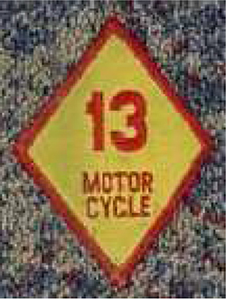 Dieses gelbe Kennzeichen mit roter Umrandung in Form einer Raute zeigt eine rote Nummer 13. Darunter ist ebenfalls in roten Großbuchstaben das Wort MOTOR und darunter CYCLE abgebildet.