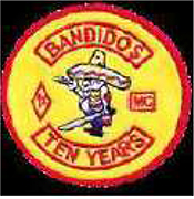 Dieses gelbe Kennzeichen mit roter Umrandung in Form eines Kreises, enthält einen nach links blickenden dickbäuchigen Mann mit Sombrero, in dem sich zwei Einschusslöcher befinden. Pistole und Schwert hält der Mann in den Händen. Ein nach obenhin gerundeter Bogen, enthält den Namen „BANDIDOS“ in roten Großbuchstaben. Ein nach untenhin gerundeter Bogen enthält die Jahresangabe „TEN YEARS“. Links des Mannes befindet sich das rautenförmige 1 Prozentzeichen rot umrandet, rechtsseitig in einem rotumrandeten Viereck die Abkürzung MC.